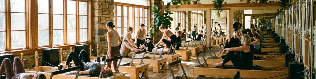 Cours collectif reformer Pilates sur machines en bois de chêne en studio lumineux