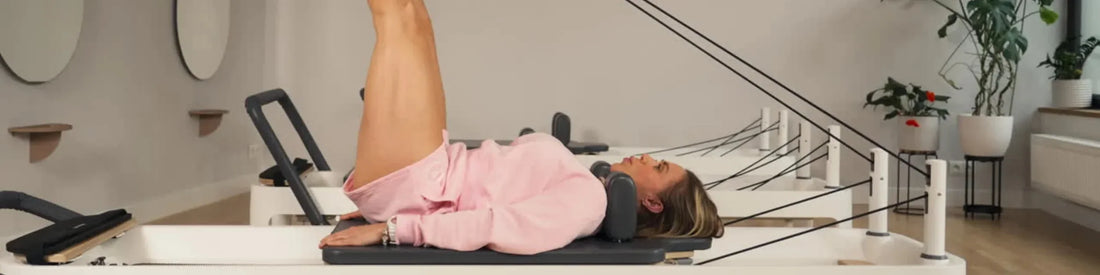 Femme en tenue rose pratiquant le Pilates sur reformer en chêne haut de gamme