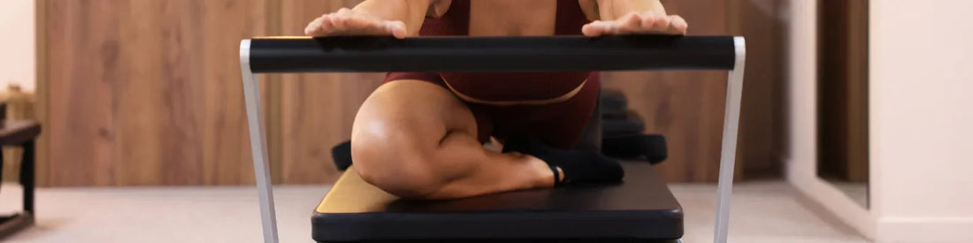 Femme pratiquant le Pilates sur reformer en chêne massif à domicile