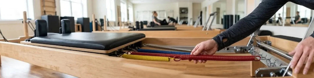 Réglage des ressorts colorés d'un reformer Pilates en bois de chêne