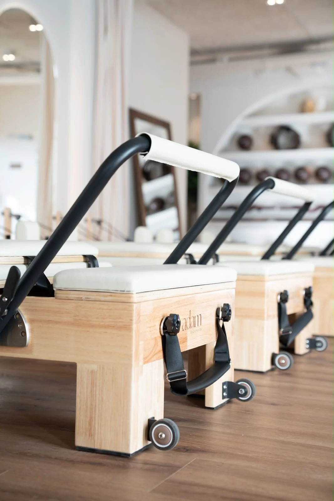 Reformers Pilates en bois alignés dans le studio Adam Pilates