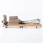Machine reformer Pilates pliable cadre bois naturel avec carriage gris taupe et sangles, vue de profil - Pilates At Home