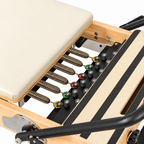 Détail des ressorts et du chariot crème du Reformer Pilates en bois clair