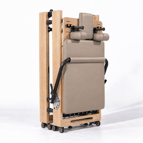 Reformer Pilates pliable en bois clair et revêtement beige, replié à la verticale