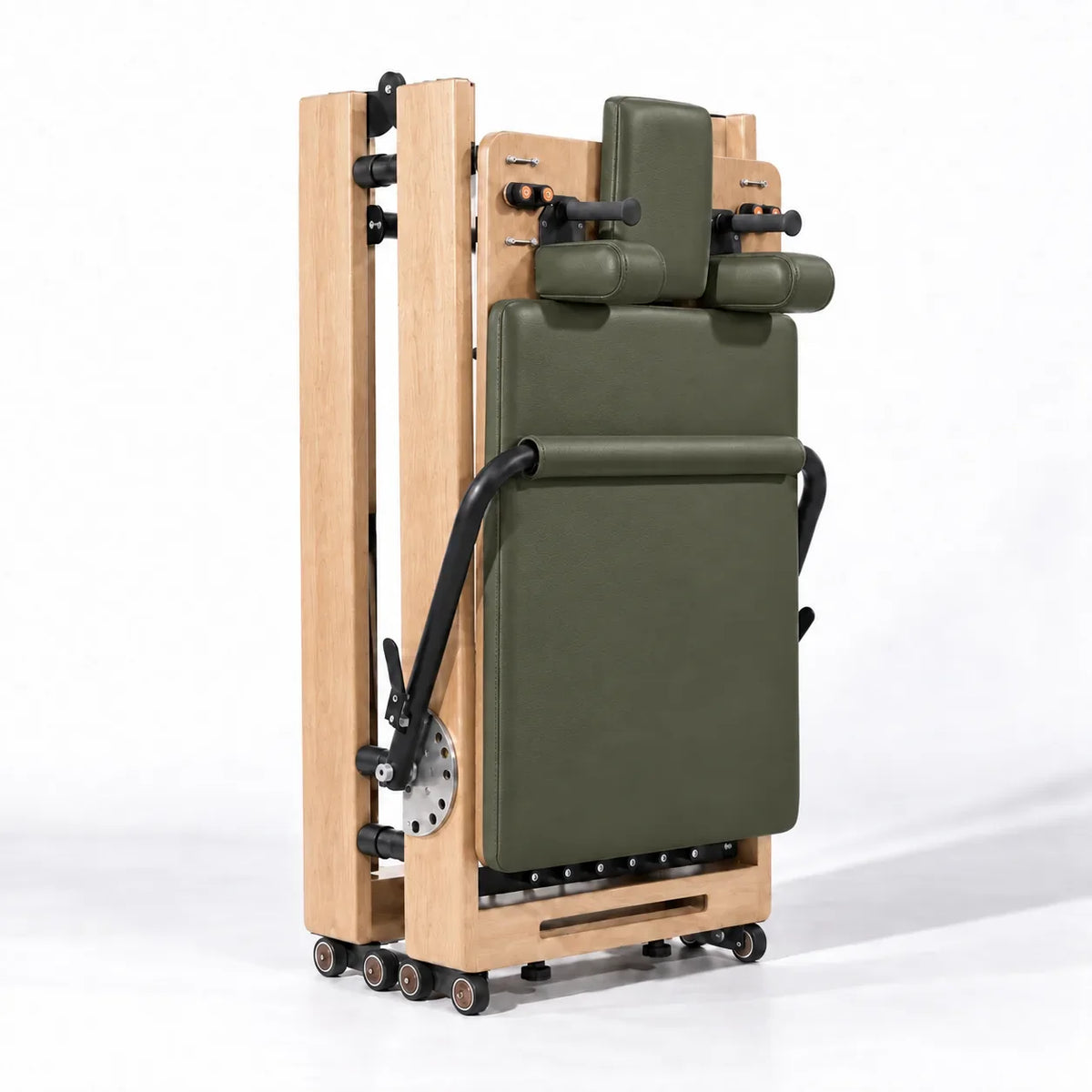 Reformer Pilates pliable en position rangée verticale, cadre bois clair et revêtement vert kaki - Pilates At Home