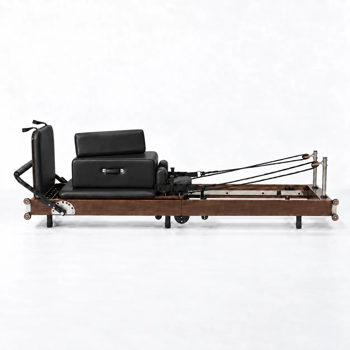 Reformer Pilates studio cadre bois foncé sellerie noire avec cordes et sangles, vue de profil - Pilates At Home