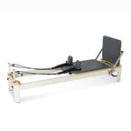 Reformer Pilates studio Signature en aluminium blanc avec carrosserie grise et footbar réglable, vue de trois quarts - Pilates At Home