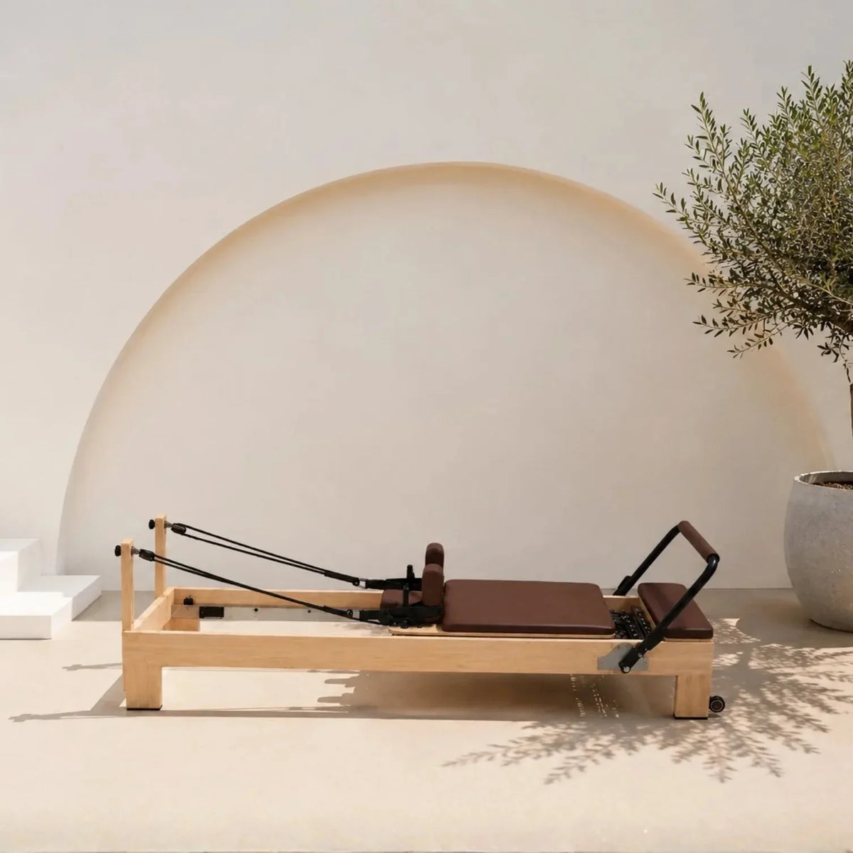 Reformer Pilates studio cadre bois naturel assise marron chocolat avec sangles, vue de profil - Pilates At Home