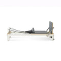 Reformer Pilates Studio Signature en aluminium blanc avec carrosserie grise et footbar réglable, vue de profil - Pilates At Home