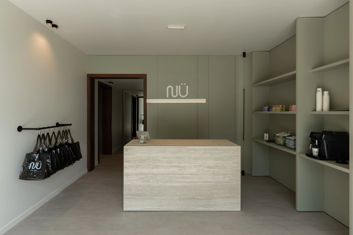 Accueil de NÜ Studio avec comptoir bois clair et mobilier vert