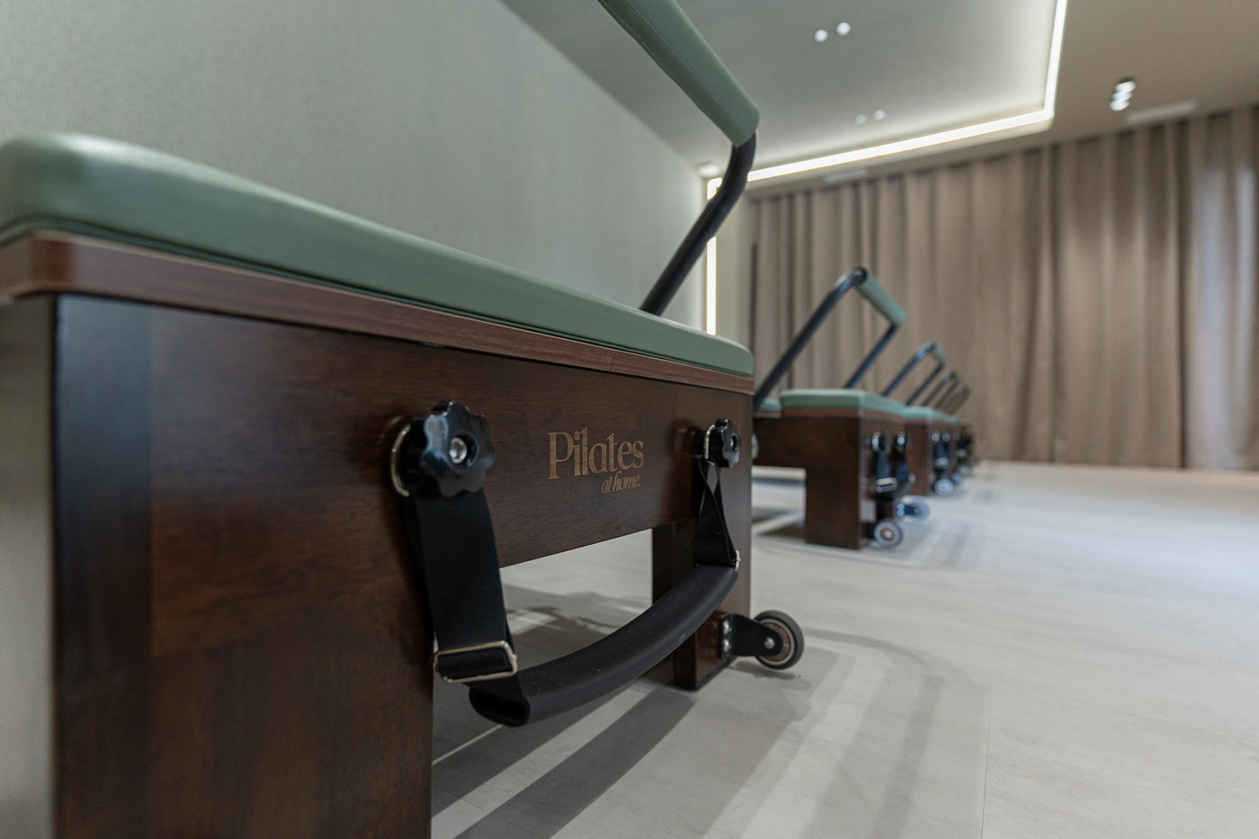 Détail des Reformers en bois et des selleries vertes de NÜ Studio Pilates